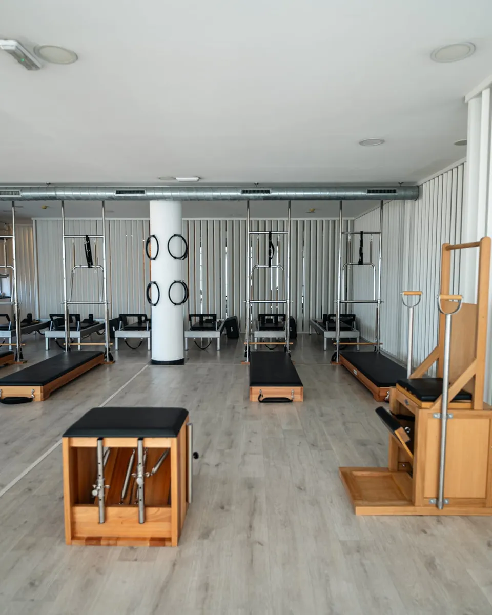 Estúdio de Pilates com reformers, cadeiras e cadillac, com muita luz natural