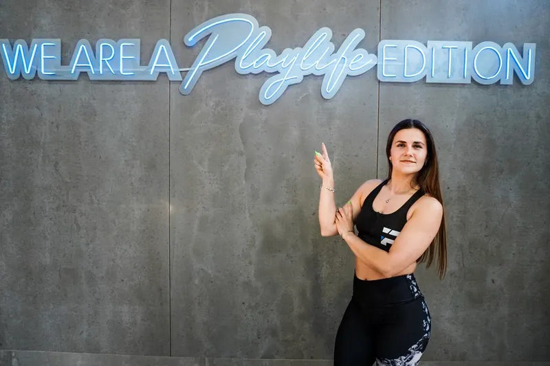 Instrutora junto ao néon «We are a Playlife edition»